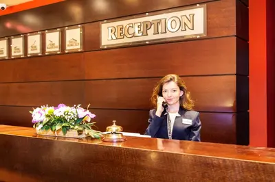 a woman talking on a phone at a reception desk at Grand Hotel Plovdiv in Plovdiv