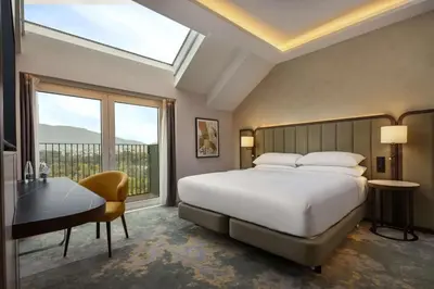 a bedroom with a bed and a desk and a window at Hilton Sofia in Sofia