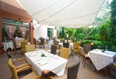 a restaurant with white tables and chairs and a large umbrella at Eurostars Sofia City in Sofia