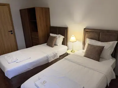 two beds in a hotel room with a lamp at Elegant Lux Hotel in Bansko