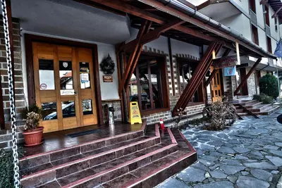 a building with wooden doors and stairs in front at Hotel Friends in Bansko