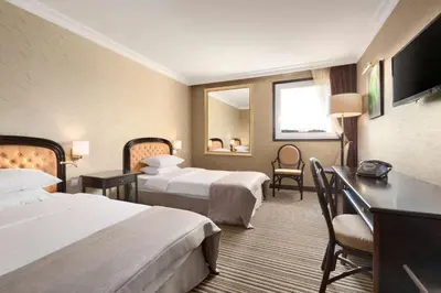 a hotel room with two beds and a desk at Ramada by Wyndham Sofia City Center in Sofia