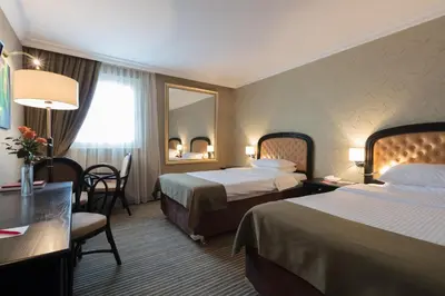 a hotel room with two beds and a mirror at Ramada by Wyndham Sofia City Center in Sofia
