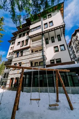 a large building with swings in front of it at Green Life Family Apartments Pamporovo in Pamporovo