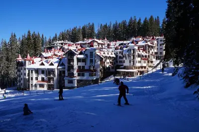 a group of people skiing in front of a resort at The Castle Complex in Pamporovo