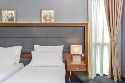 a bedroom with two beds and a table with a lamp at Budapest Hotel - Free Parking in Sofia