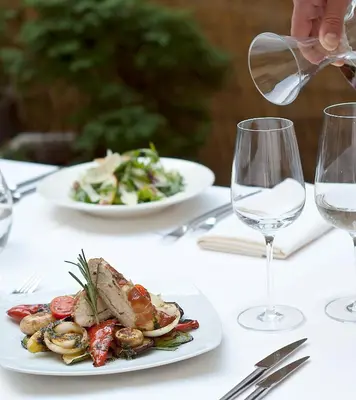 a person is pouring wine into a plate of food at Budapest Hotel - Free Parking in Sofia