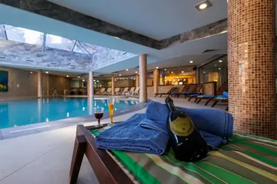 a bed with a bottle of wine on it next to a swimming pool at Vihren Royal Palace in Bansko