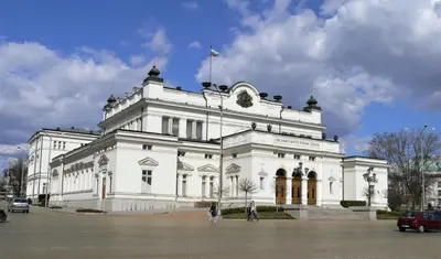a white building with a flag on top of it at Best Choice Apartment in Sofia