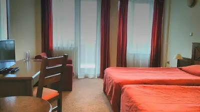 a hotel room with two beds and a table and a desk at Evelina Palace Hotel in Bansko