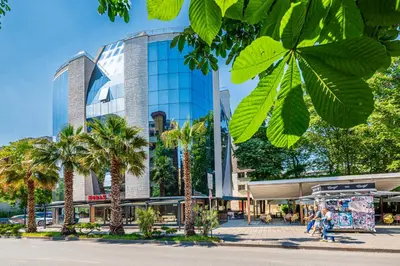 a tall glass building with palm trees in front of it at Hotel Noris in Plovdiv