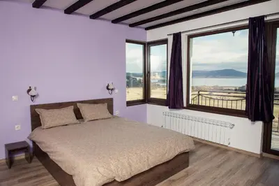 a bedroom with a bed and a large window at Vila Lidia in Tsigov Chark