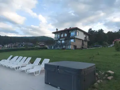 a group of white chairs and a large house at Vila Lidia in Tsigov Chark