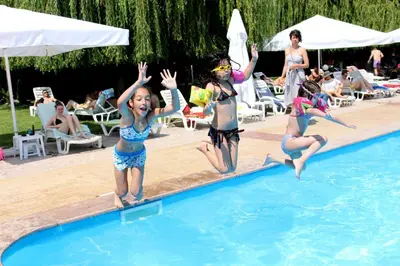a group of girls jumping into a swimming pool at Hotel Racic Self-Check In in Voyvodinovo