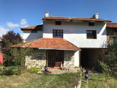 a white house with people sitting in front of it at Das Landhaus in Bachevo