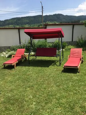 two red chairs and a red canopy in the grass at Villa Paradise in Beli Iskar