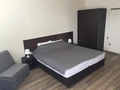 a bedroom with a large bed and a chair at Rooftop Oscar Rooms in Sofia