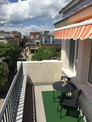 a patio with a table and chairs on a balcony at Rooftop Oscar Rooms in Sofia
