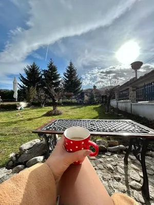 a person holding a cup of coffee at a picnic table at Guest House Rila in Govedartsi
