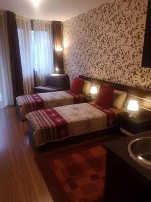 a hotel room with two beds and a chair at Snowdrop Studio in Borovets