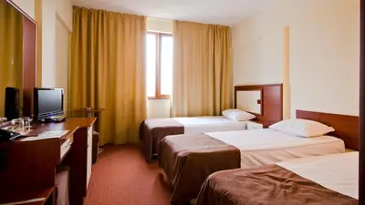 a hotel room with two beds and a desk at Nadejda Hotel in Sofia