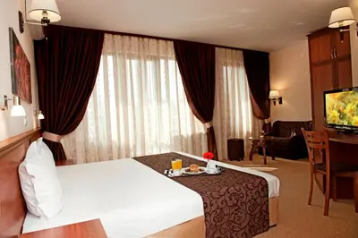 a hotel room with a bed and a table and a television at Favorit Hotel in Sofia