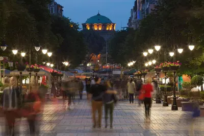 a crowd of people walking down a street at night at Central Apartment in Sofia