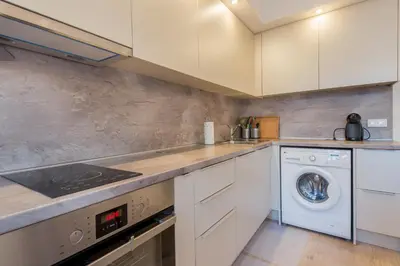 a kitchen with white cabinets and a washer and dryer at CHIC and Spacious Apartment in Central Sofia - Patriarh Evtimiy by Flat Mаnager in Sofia