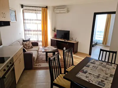 a kitchen and a living room with a table and chairs at EFO Apartment in Bansko