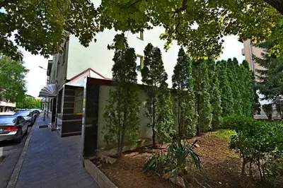 a fence with trees on the side of a street at Hotel Rai in Sofia