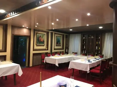 a dining room with white tables and red chairs at Hotel Rai in Sofia