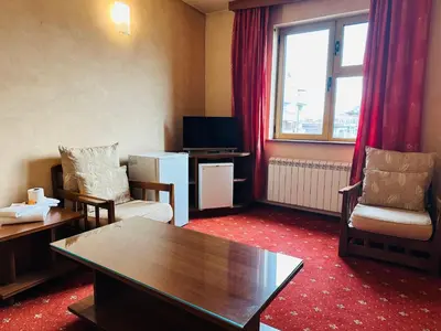 a living room with a table and chairs and a tv at Hotel Rai in Sofia