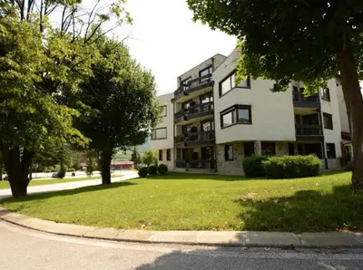 a large apartment building on a street with trees at Pravets Resort Apartments in Pravets