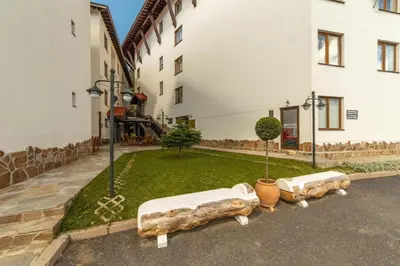 a courtyard with three benches in front of a building at Apartment Biliana in Pamporovo