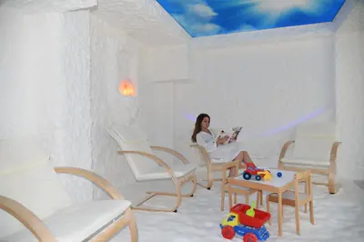 a woman sitting in a room with white chairs at SPA Hotel Olymp in Velingrad