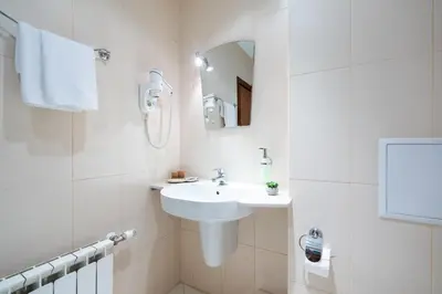 a white bathroom with a sink and a mirror at Hotel Hadjiite in Koprivshtitsa