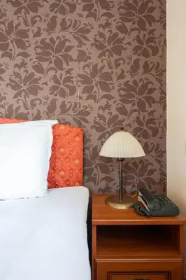 a bedroom with a bed and a lamp on a night stand at Hotel Hadjiite in Koprivshtitsa