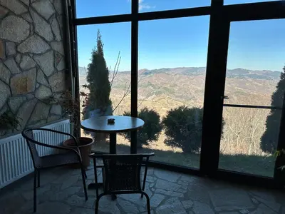 a table and chairs in a room with a large window at Karadzhovata Kashta in Zlatograd
