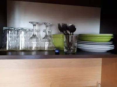 a shelf with plates and glasses and bowls and utensils at City Sandanski in Sandanski