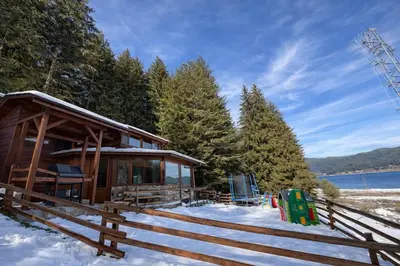 a log cabin in the snow with a fence at Villa Raiski kyt in Dospat