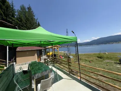 a green tent sitting next to a body of water at Villa Raiski kyt in Dospat