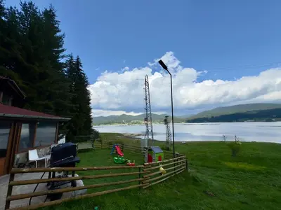 a house with a fence next to a body of water at Villa Raiski kyt in Dospat