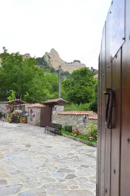 a stone courtyard with a bench in front of a building at Family Hotel Dinchova kushta in Rozhen