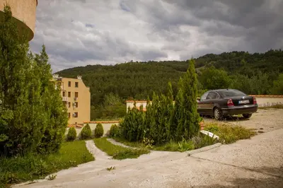 a car parked in a parking lot next to a building at Вихрен-стаи и апартаменти за гости in Sandanski