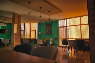 a dining room with green walls and tables and chairs at Вихрен-стаи и апартаменти за гости in Sandanski