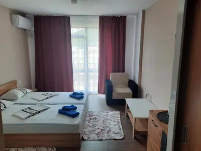 a hotel room with two beds and a chair at Вихрен-стаи и апартаменти за гости in Sandanski
