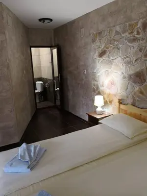 a bedroom with a large bed and a stone wall at Yurukovata kashta in Koprivshtitsa