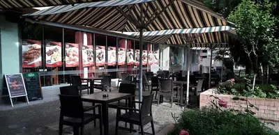 a restaurant with tables and chairs under an umbrella at Heat Complex Family Hotel in Peshtera