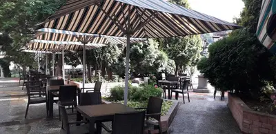 a restaurant with tables and chairs under an umbrella at Heat Complex Family Hotel in Peshtera