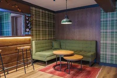 a living room with a couch and a table and stools at Iglika Hotel & Villas Borovets in Borovets